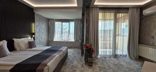 a bedroom with a large bed and a large window at SPA Hotel Olymp in Velingrad