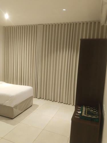 a bedroom with a bed and a window with curtains at شقة فاخرة بغرفتين وحمامين وصالة جلوس وصالة طعام in Al Madinah
