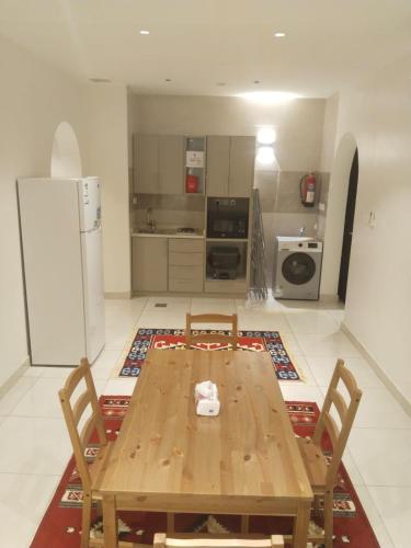a kitchen with a wooden table and chairs in it at شقة فاخرة بغرفتين وحمامين وصالة جلوس وصالة طعام in Al Madinah