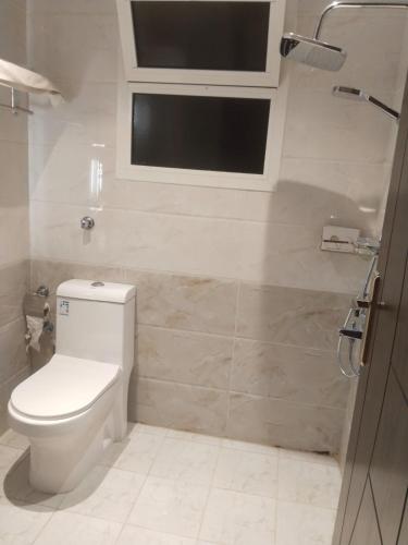 a bathroom with a toilet and a television on the wall at شقة فاخرة بغرفتين وحمامين وصالة جلوس وصالة طعام in Al Madinah