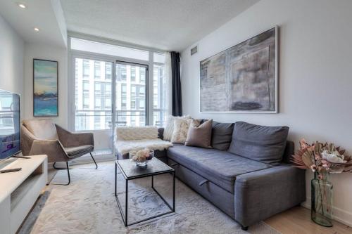 a living room with a couch and a tv at Modern 2 Bedroom plus Den Condo with Balcony Downtown Toronto in Toronto