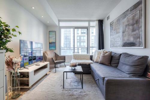 a living room with a couch and a tv at Modern 2 Bedroom plus Den Condo with Balcony Downtown Toronto in Toronto