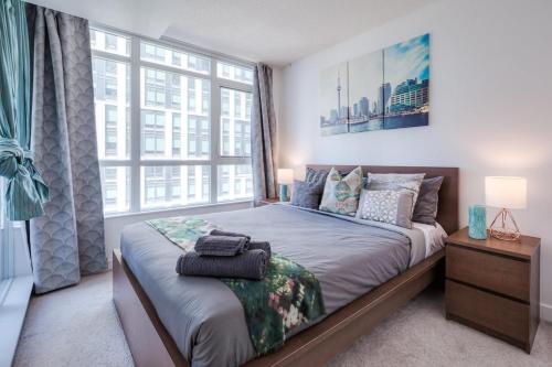 ein Schlafzimmer mit einem Bett mit einem großen Fenster in der Unterkunft Modern 3Br Condo with Balcony Downtown Toronto in Toronto