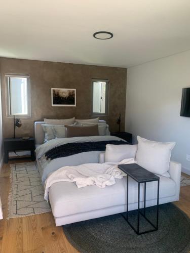 a bedroom with a bed and a white couch at Tide and Timber Luxury Guesthouse in Hermanus