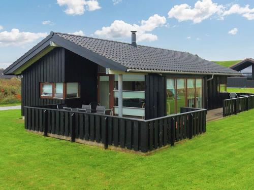 a black house with a fence in front of it at 5 star holiday home in Hjørring in Lønstrup