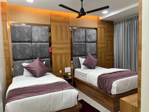 a bedroom with two beds and a ceiling fan at Hotel Narayan Villa in Rājahmundry