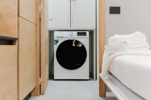a washer and dryer in a room next to a bed at Borgo apartment - Vicino Centro in Belluno