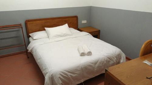 a bedroom with a white bed with two slippers on it at Heeren Street Boutique Hotel at Jonker Walk in Melaka