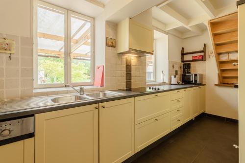 a kitchen with white cabinets and a sink and a window at De Groene Hoeve in Brakel