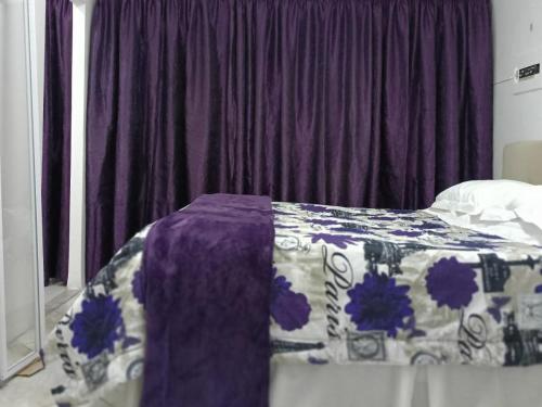 a bedroom with a bed with a purple blanket on it at Sarah's Place Guesthouse in Pretoria