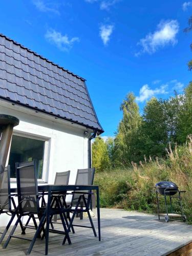 a patio with a table and chairs and a grill at Fritids hus nära natur in Skärsnäs