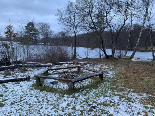 a bench sitting in the snow next to a lake at Fritids hus nära natur in Skärsnäs