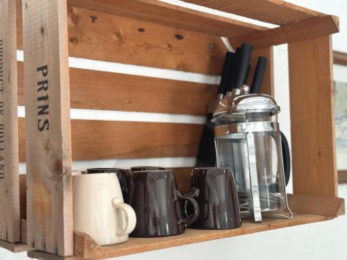 a wooden shelf with mugs and a tea pot at The Smythy Cotswolds Farm Stay With Pool in Lechlade