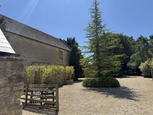 a wooden bench sitting next to a building with a tree at The Smythy Cotswolds Farm Stay With Pool in Lechlade