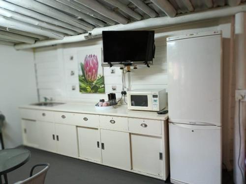 a kitchen with a white refrigerator and a microwave at Sarah's Place Guesthouse in Pretoria