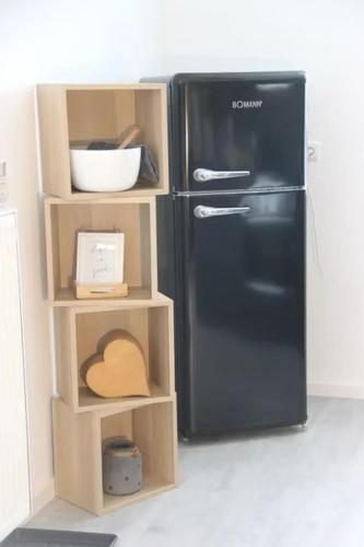a toy kitchen with a black refrigerator and shelves at Ferienwohnung Kleine Auszeit in Schweich