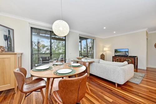 a living room with a table and a couch at Hole in One Villa with Free Wine Tasting in Pokolbin