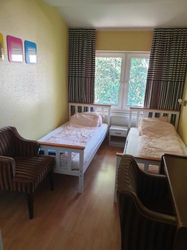 a bedroom with two beds and a chair and two windows at Famile Hotel Kameleon in Olsberg