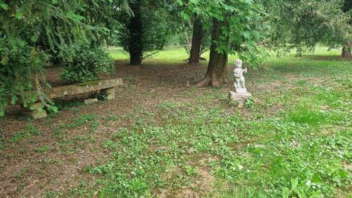 a park with a statue and a bench and trees at Gîte du château de Chevannes in Amazy