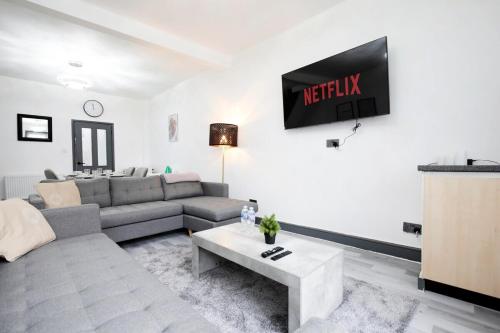 a living room with a couch and a tv on the wall at Dixon House, Sleeps 6, Free Parking, Long or Short Stays - by NMB Property in Horwich