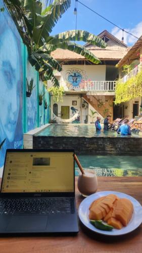 a laptop computer sitting on a table with a plate of food at Tipsea Turtle Gili Air in Gili Air