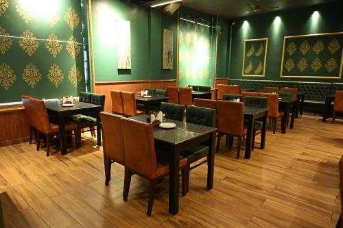 a restaurant with tables and chairs and green walls at Hotel Golden Fern in Patiāla