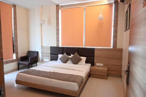 a bedroom with a bed and a chair and a window at Hotel Golden Fern in Patiāla