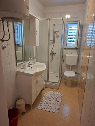 a bathroom with a sink and a shower and a toilet at Apartmani Dijana in Rab