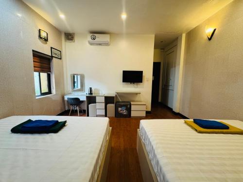 a room with two beds and a desk with a television at Sword Lake hostel in Hanoi