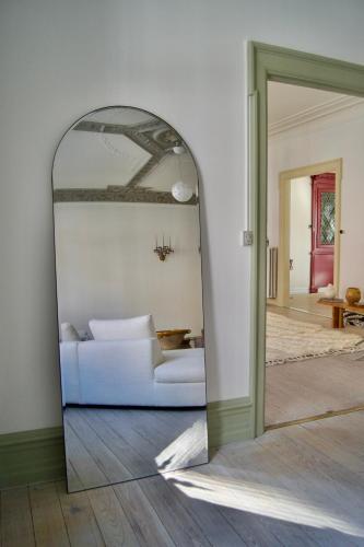a living room with a white couch and a mirror at SJ Apartment in Aarhus