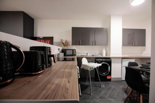 a kitchen with black and white cabinets and wooden floors at Bartlam Place, Sleeps 6, Central Oldham - By NMB Property in Oldham