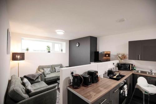 a kitchen and living room with a couch and a table at Bartlam Place, Sleeps 6, Central Oldham - By NMB Property in Oldham