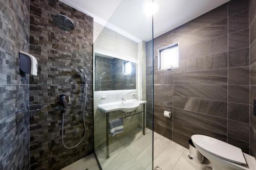 a bathroom with a toilet and a sink and a shower at Caretta Paradise Resort & WaterPark in Tragaki