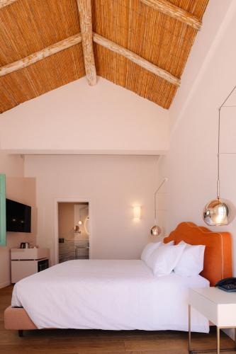 a bedroom with a white bed with a wooden ceiling at Casa di Nonno in Serdiana