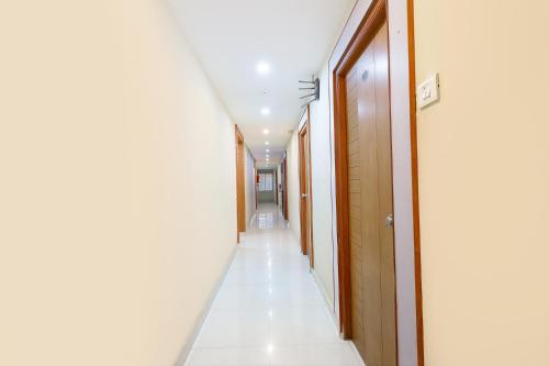 a long corridor with white floors and wooden doors at FabHotel RKH Skyline Residency in Chennai