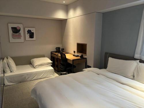a hotel room with two beds and a desk at K Hotel Taipei Nanjing in Taipei