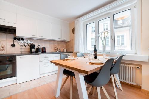 a white kitchen with a wooden table and chairs at Alpenheim Apartment in Andermatt