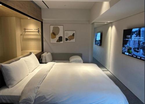 a bedroom with a large white bed and a tv at K Hotel Taipei Nanjing in Taipei