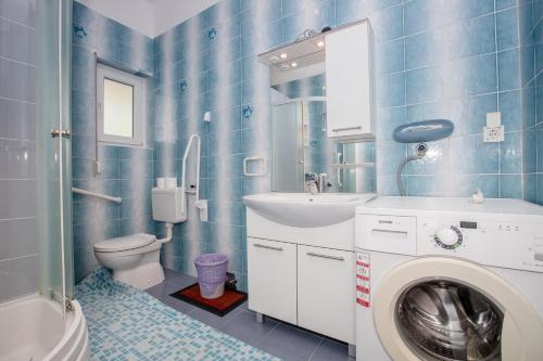 a blue tiled bathroom with a washing machine in it at Eg Marjetka Bis 9 in Rab