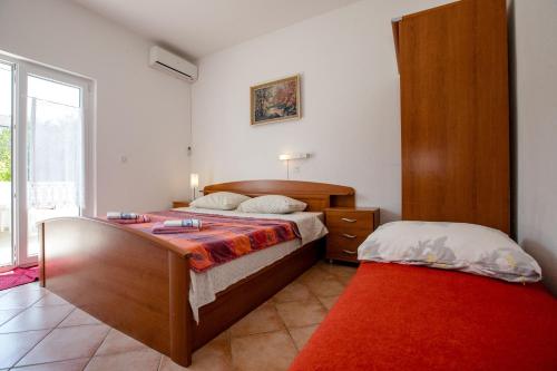 a bedroom with two beds and a red rug at Eg Marjetka Bis 9 in Rab