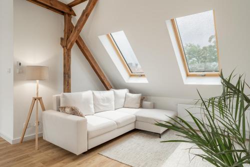 a white couch in a living room with two windows at Apartamenty SWAN in Gliwice