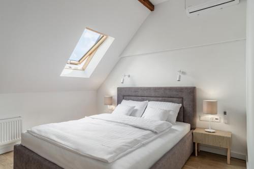 a bedroom with a bed with white sheets and a window at Apartamenty SWAN in Gliwice