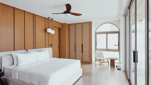 a bedroom with a white bed and a ceiling fan at villaSAMU in Amphoe Koh Samui