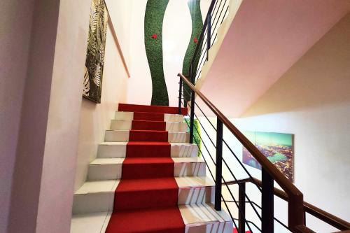 a staircase with red and white carpet and a painting at DLT Suites Cebu powered by Cocotel in Minglanilla