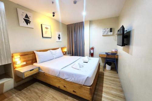 a hotel room with a bed and a television at DLT Suites Cebu powered by Cocotel in Minglanilla