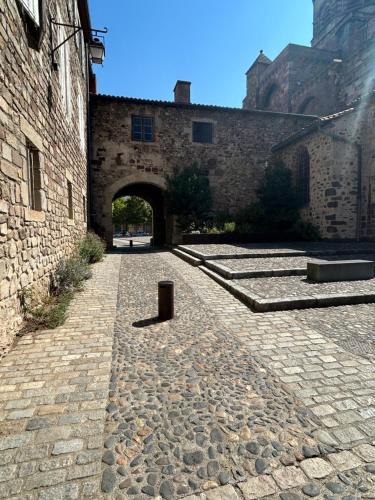a stone courtyard with an archway in a brick building at Relais du Noble Voyageur in Brioude