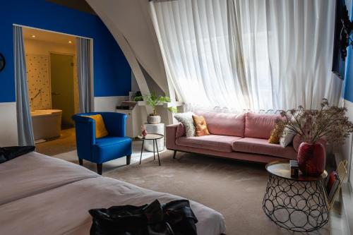 a bedroom with a pink couch and a blue chair at Librije's Hotel in Zwolle