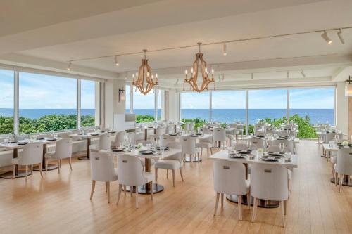 a dining room with white tables and chairs and windows at IRAPH SUI, a Luxury Collection Hotel, Miyako Okinawa in Miyako Island