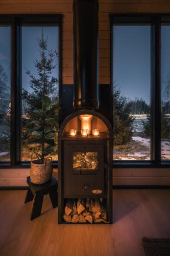 a fireplace with a stove in a room with windows at Piilotupa in Inari