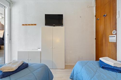 a room with two beds and a tv on a wall at Tirreno 304 in La Pineda